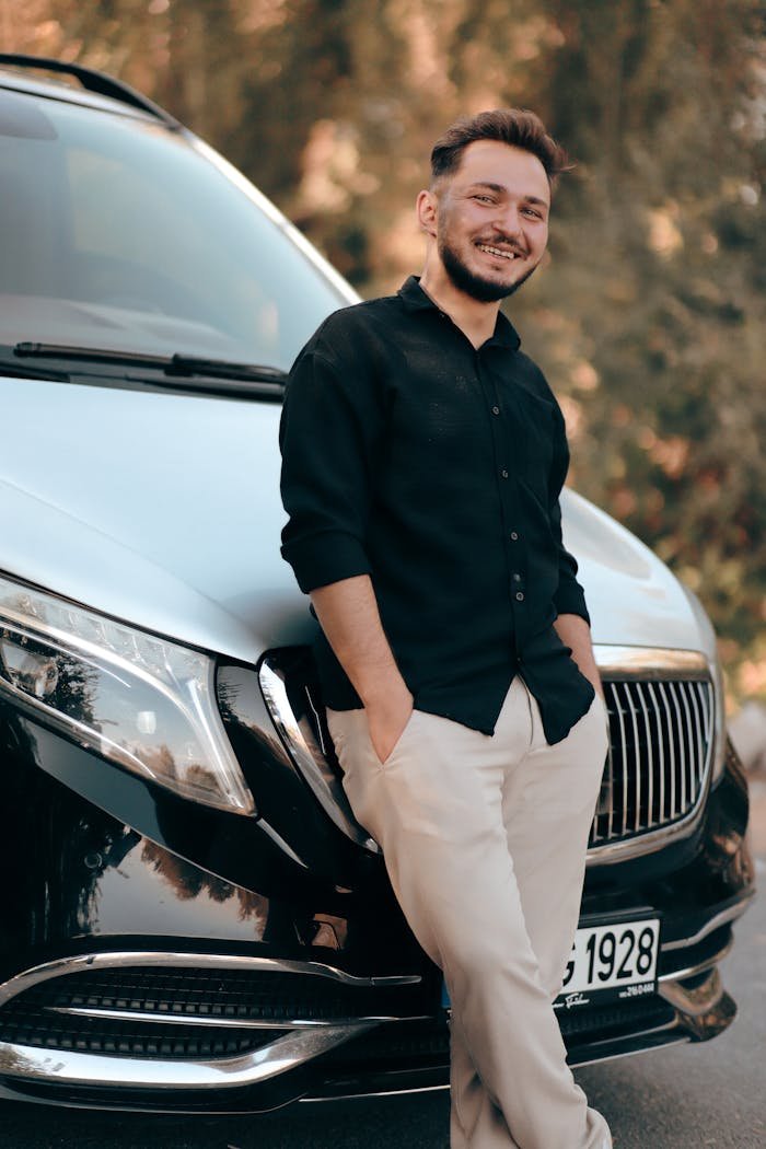 The Art of Drawing Readers In: Your attractive post title goes here Casually dressed man smiling and leaning against a luxury car on a sunny day.