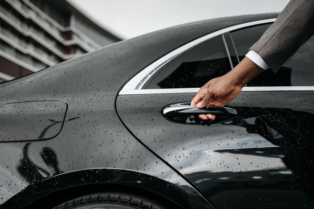 Crafting Captivating Headlines: Your awesome post title goes here A close-up of a hand opening a black car door covered in raindrops, showcasing elegance and weather detail.